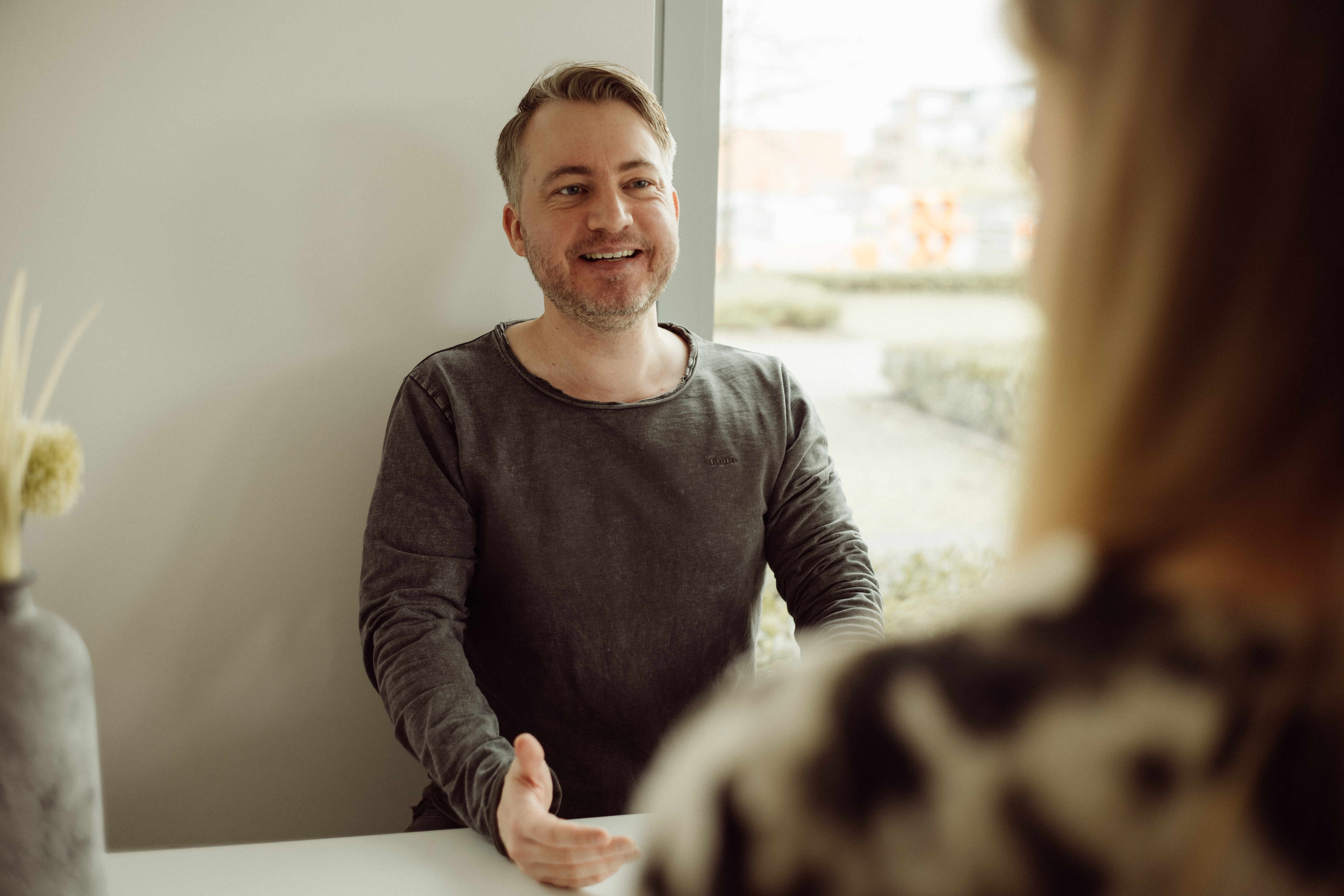 Freundliche:r Mitarbeiter:in des Unternehmens in Arbeitskleidung, lächelnd in die Kamera blickend