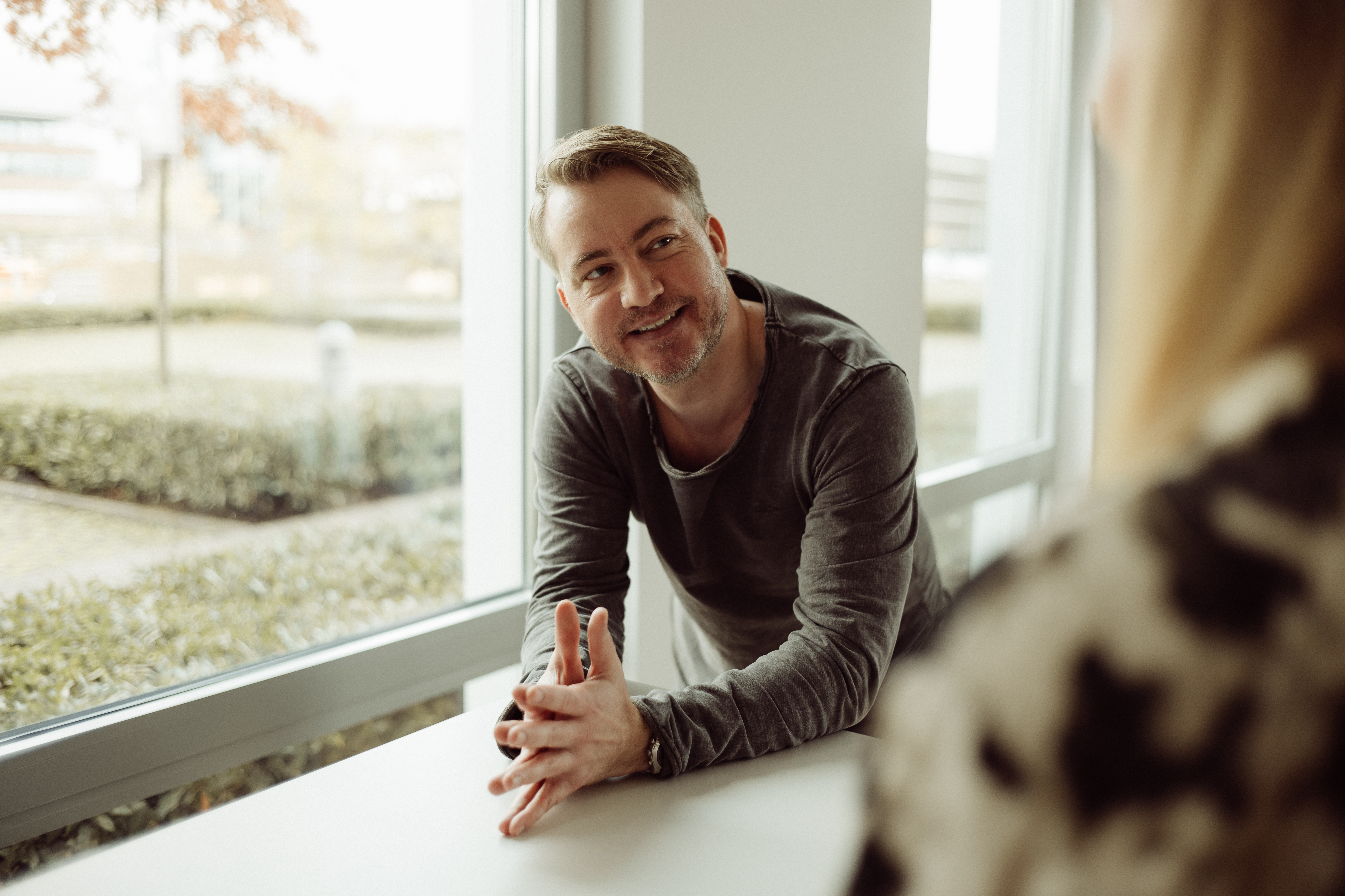 Freundliche:r Mitarbeiter:in des Unternehmens in Arbeitskleidung, lächelnd in die Kamera blickend